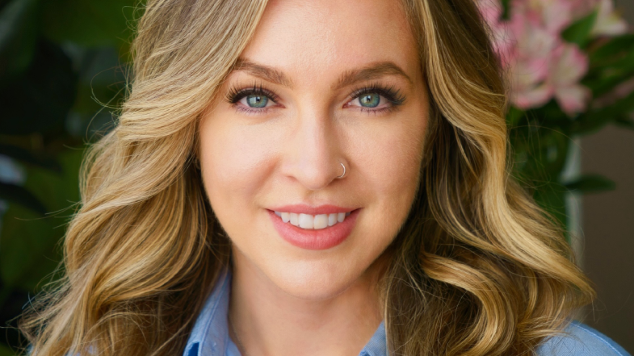 Headshot portrait of a smiling woman with long wavy blonde hair and blue blouse