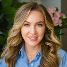 Headshot portrait of a smiling woman with long wavy blonde hair and blue blouse